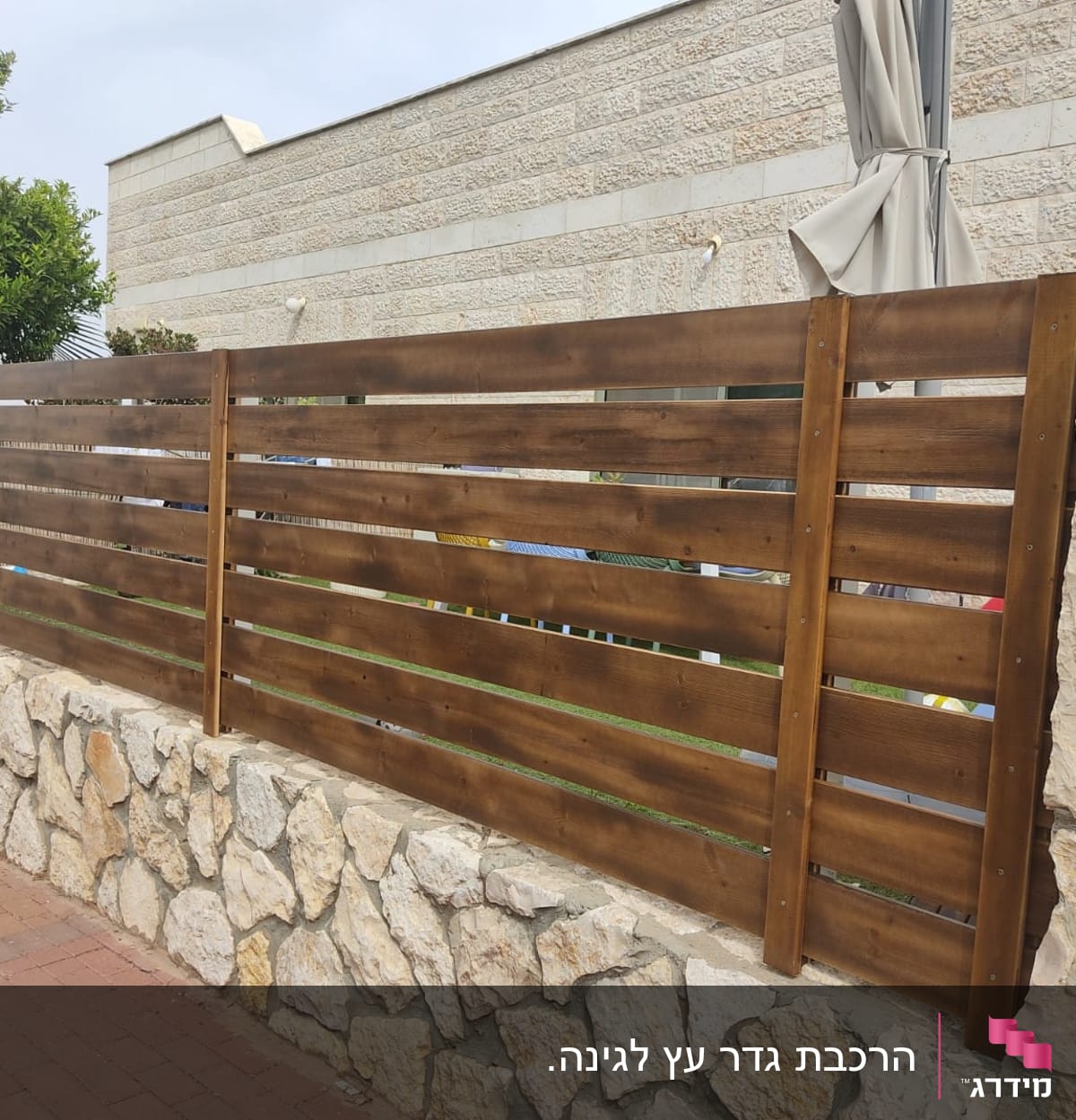 גדר עץ חומה על קיר אבן בגינה